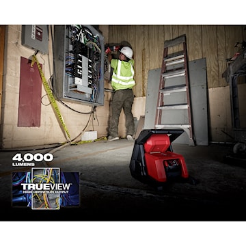 Électricien travaillant sur un panneau électrique ouvert avec une lampe de chantier LED rouge portable offrant 4000 lumens